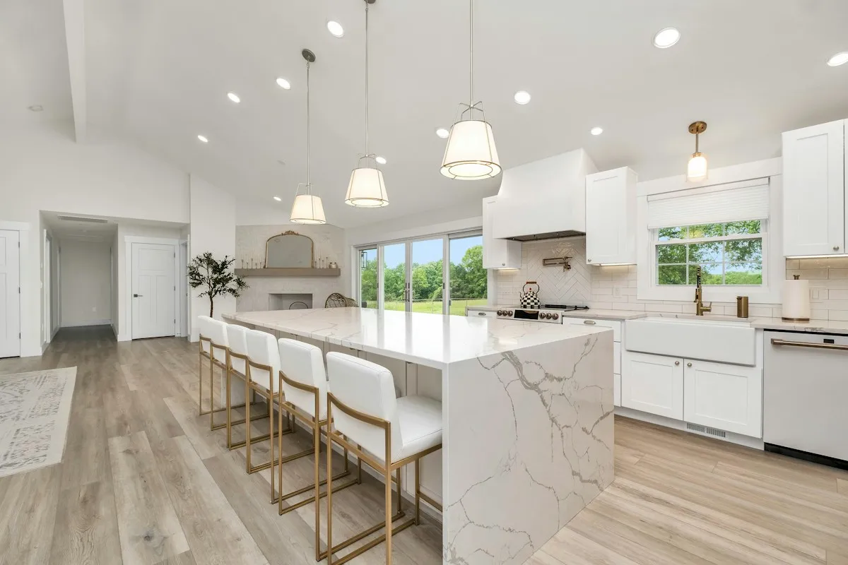 Finished white kitchen with a large marble island and pendant lighting