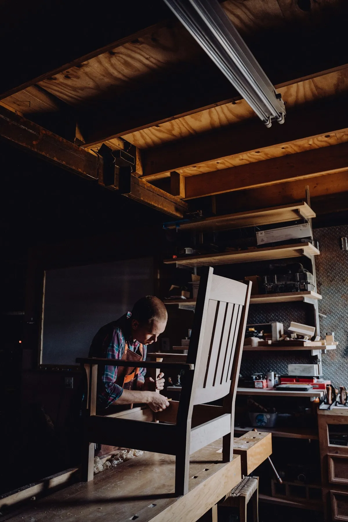 Carpenter assembling a wooden chair frame in a workshop