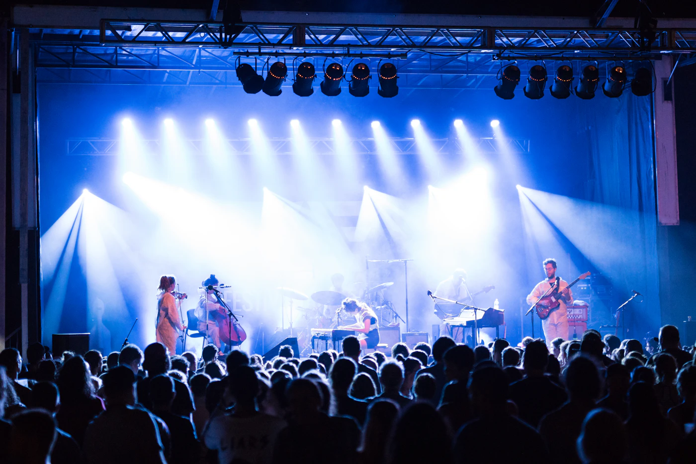 A four-piece band playing on a small stage under red and blue lights