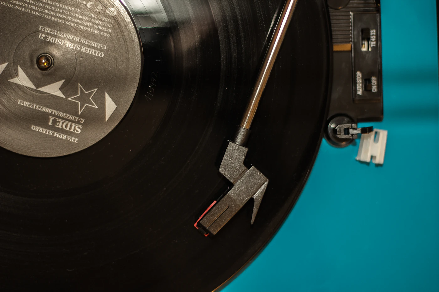 A black vinyl record playing on a turntable, the tone arm resting on the groove