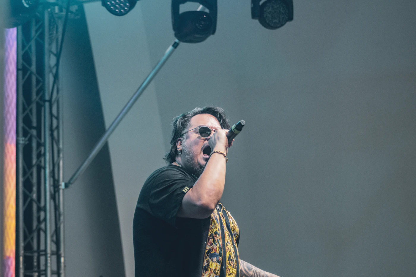 A singer at a microphone under pink stage light
