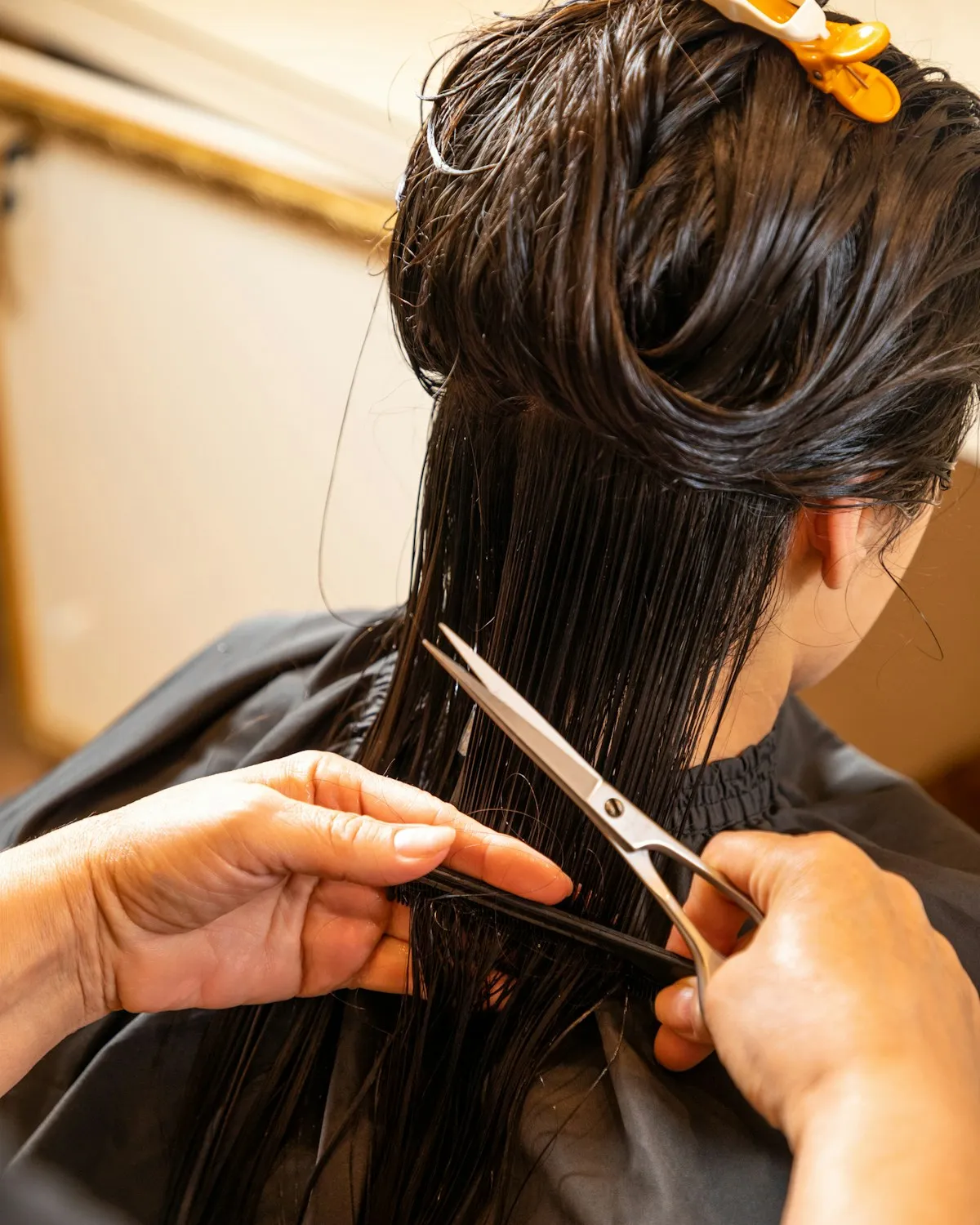 Close-up of a stylist trimming wet hair with scissors